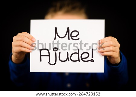 Studio shot of child holding a sign with Portuguese words Me Ajude - Help Me