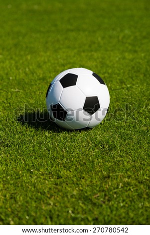 Black and white soccer ball on green soccer pitch.