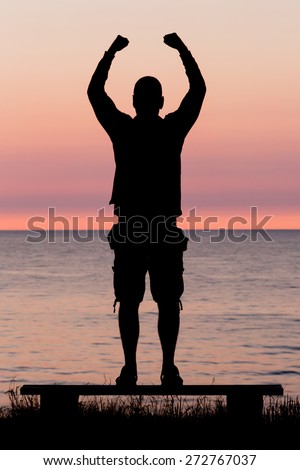 Silhouette of male person against a colorful horizon.