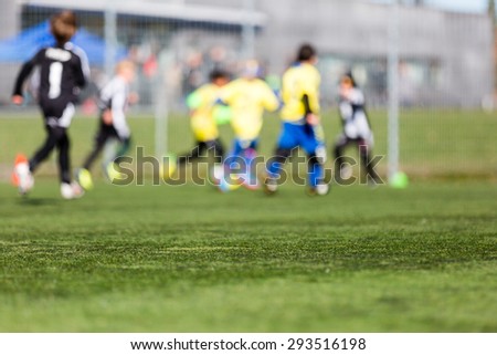 Blur of young boys playing a kids soccer match outdoors on an green soccer pitch.