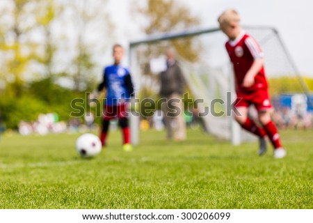 Shallow depth of field shot of young boys playing a kids european football match on green grass.