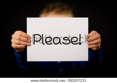 Studio shot of child holding a Please sign made of white paper with handwriting.