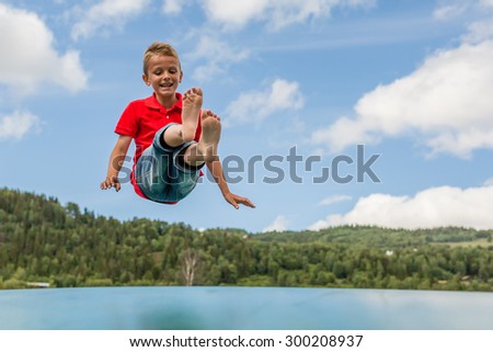 Young Scandinavian boy playing and having fun while jumping up and down on inflatable bouncing pillow.