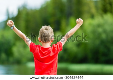 Young boy raising his hands in the air and celebrating success or victory.