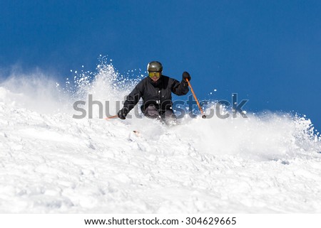 Male skier skiing off piste in powder snow a sunny winter day.