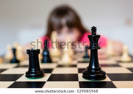 Young white child playing a game of chess on large chess board.