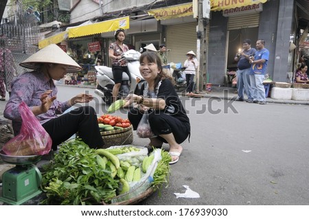 HANOI, VIETNAM - MAY 24: Unidentified street peddler selling vegetables to her customer on May 24, 2011 in Hanoi, Vietnam.