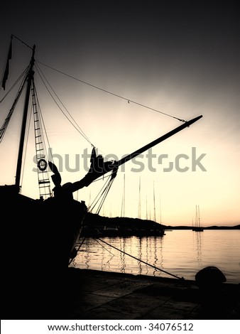 Sepia toned image and silhouette of an old ship in the Adriatic port in the quiet and tranquil  evening.