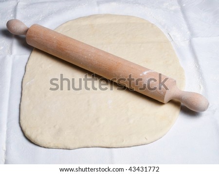 Rolling pin and dough during food preparation.