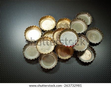 Lot of bottle caps on a gray background with pattern.