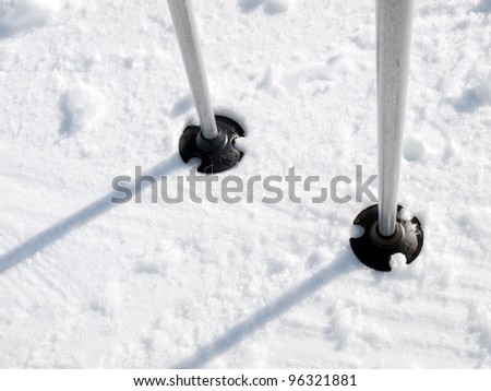 Closeup view on the lower part of the ski poles in the snow.