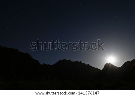 Moon rising over the silhouetted Tinajas Altas Mountains in Arizona, USA. Nice clean lines of the mountains along the horizon. Dark night gives impression of desolation in the Sonoran Desert.