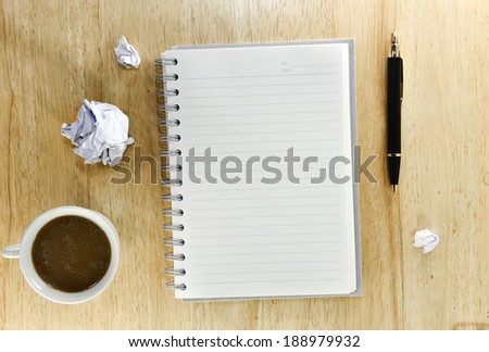 working table conceptof notebook,pen,coffee and paper crumpled on wooden background