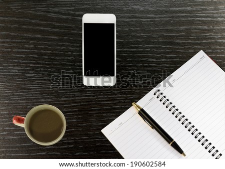 Workplace with phone,notebook, pen and cup of coffee on work table top view