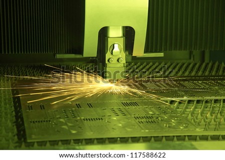 Industrial laser cutter with green background, with sparks