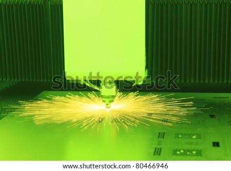 Industrial laser cutter with green background, with sparks