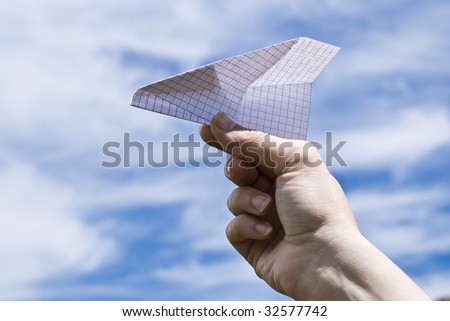 Hand holding a paper airplane on sky background