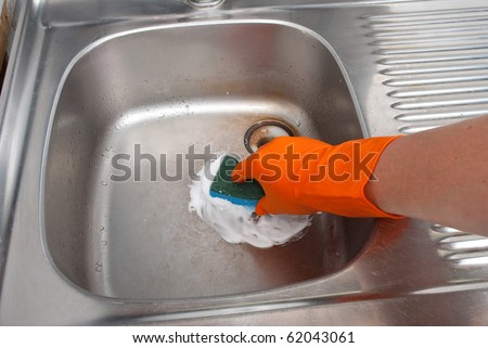 Person cleaning the kitchen sink with a glove