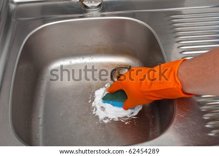 Person cleaning the kitchen sink with a glove