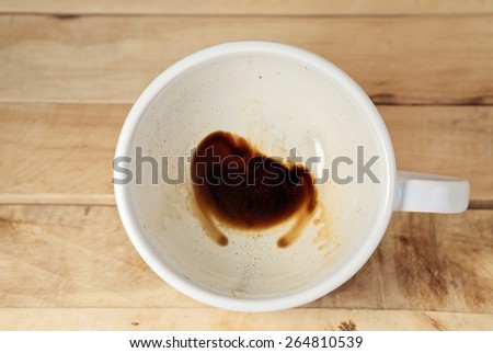 Coffee cup with coffee stains have not washed the cup placed on the wooden floor. Top view.