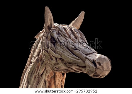 Horse head made of scrap wood on black background.