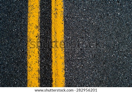 Double yellow line on black asphalt road.