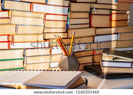 Open book, textbook, laptop, pencils in library, stack piles of literature text archive, bookshelves in school study class room background for academic education learning concept