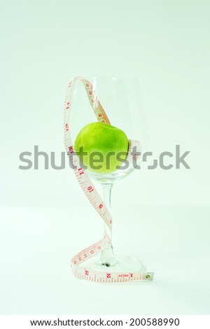 wine glass filled with green apple with the measure tape.