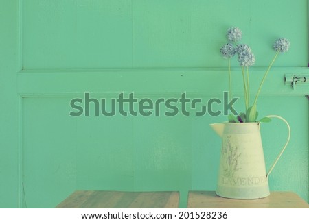 violet flower  in an  aluminum vase over green background.