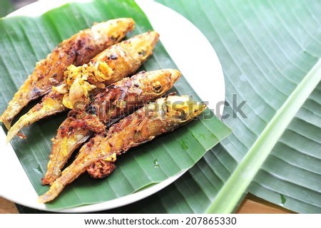 fired fish with garlic and turmeric on banana leaf,thai food