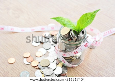 Plant and coins in jar with measure tape,save money concept.