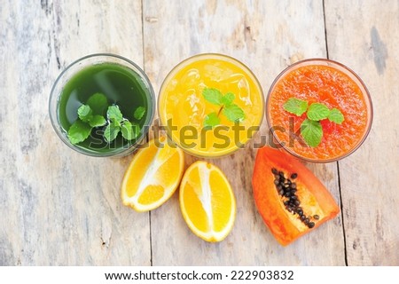 Orange juice with papaya smoothie and mint leaves smoothie on wooden background.