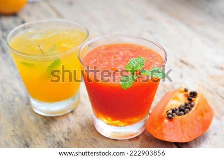 Orange juice with papaya smoothie on wooden background.