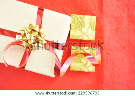 Gift box with red ribbon bow on red paper.