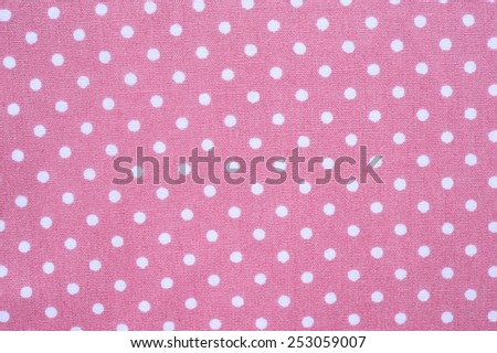 White polka dots on a tile pastel pink fabric background.
