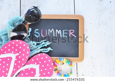 beach accessories and small black board on wooden board.