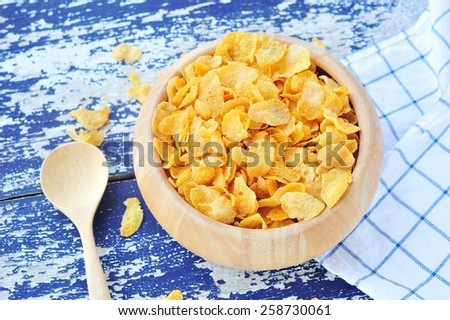 Wooden bowl of corn flakes on vintage table.