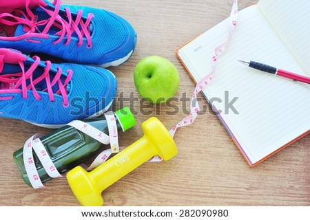 Fitness concept ,fresh fruits, juice bottle and record book on tile floor.