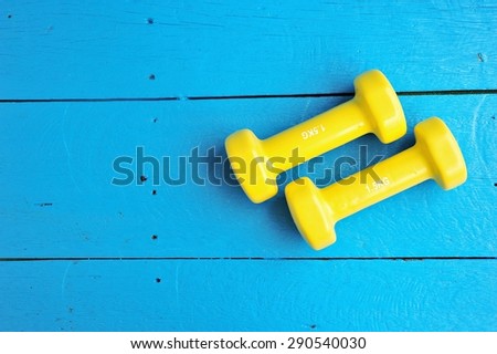 Yellow dumbbells  plank on blue painted wood background.