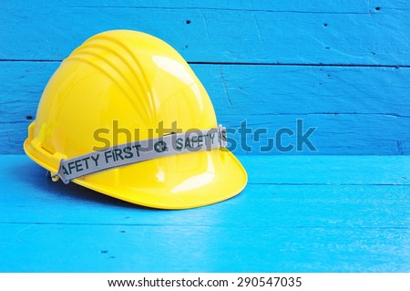 Yellow safety hard hat on blue wooden background.