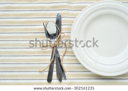 Empty dish, knife and fork on table cloth.
