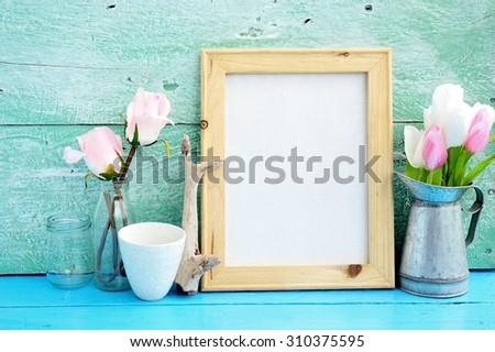 Vintage blank wooden frame, bottles ,flower on paint wood background.