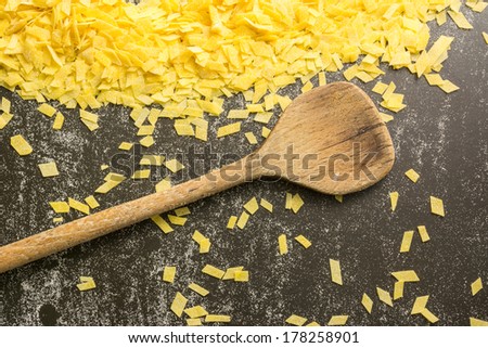 Grandmother\'s home made pasta and a kitchen spoon on black surface, beautiful yellow black background