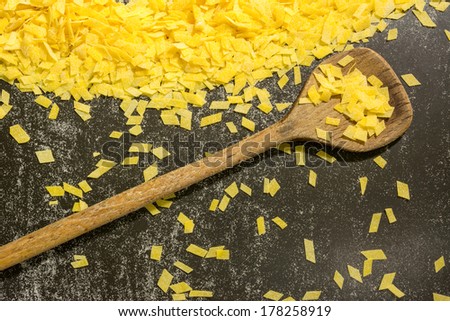 Grandmother\'s home made pasta and a kitchen spoon on black surface