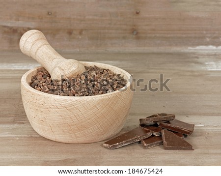 Cacao nibs in pestle with chunks of chocolate