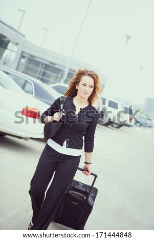 Travel: Woman Pulling Suitcase Through Airport Parking Lot