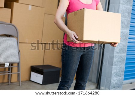Storage: Anonymous Woman Holding Box By Storage Unit
