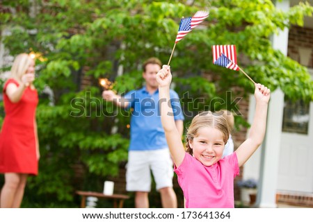 July 4th: Excited Little Girl Holding Flags in the Air
