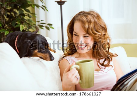 Pets: Woman Has Cup Of Coffee with Dog On Couch