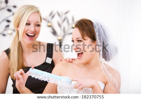 Bride: Bride and Friend Having Fun with Garter